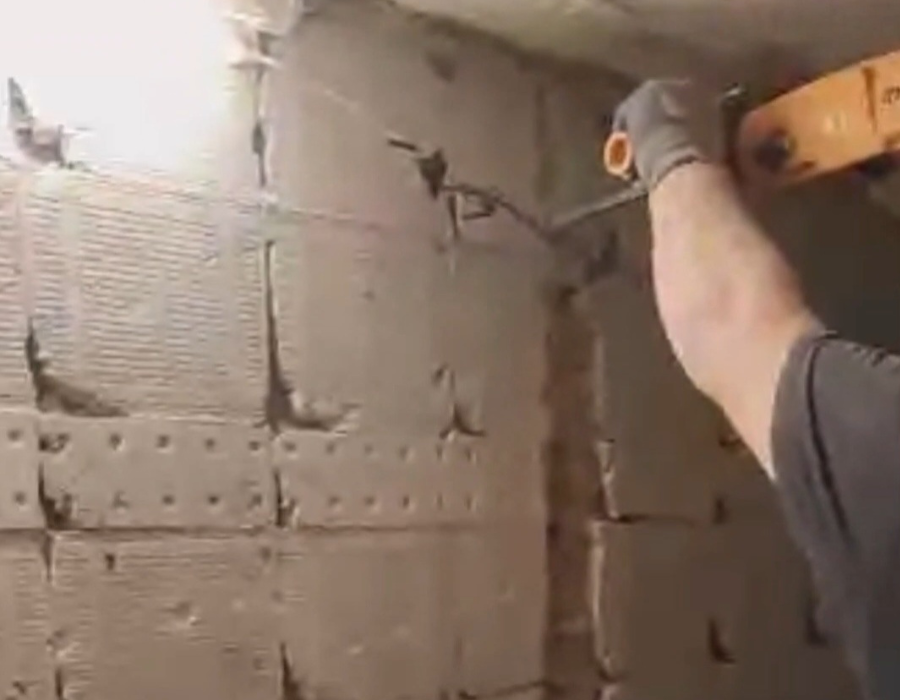 Ένα χέρι κρατάει τρυπάνι και σκάβει τον τοίχο για να γίνει η ανακαίνιση ενός μπάνιου